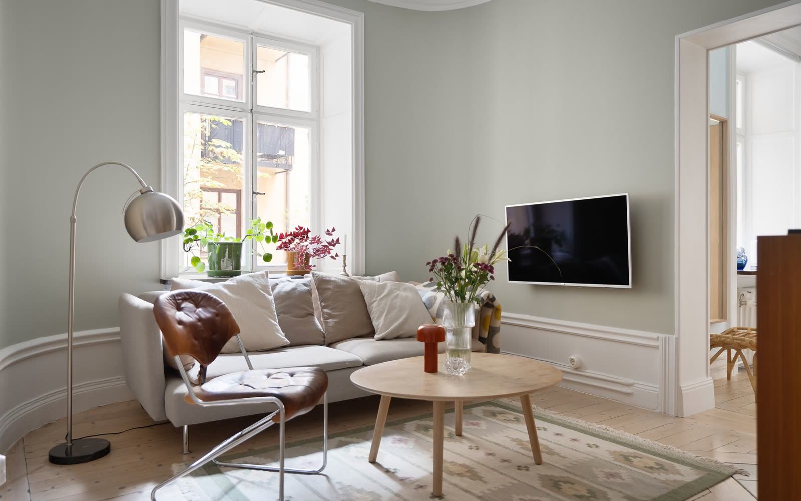Grönt vardagsrum med soffa, tv och gammalt trägolv