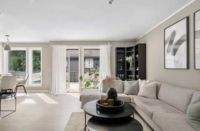 Beige vardagsrum med stor soffa och altandörr
