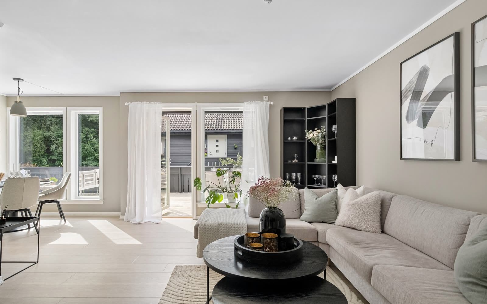 Beige vardagsrum med stor soffa och altandörr