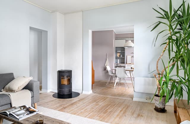 Vardagsrum med kamin, öppning mot kök och plankgolv