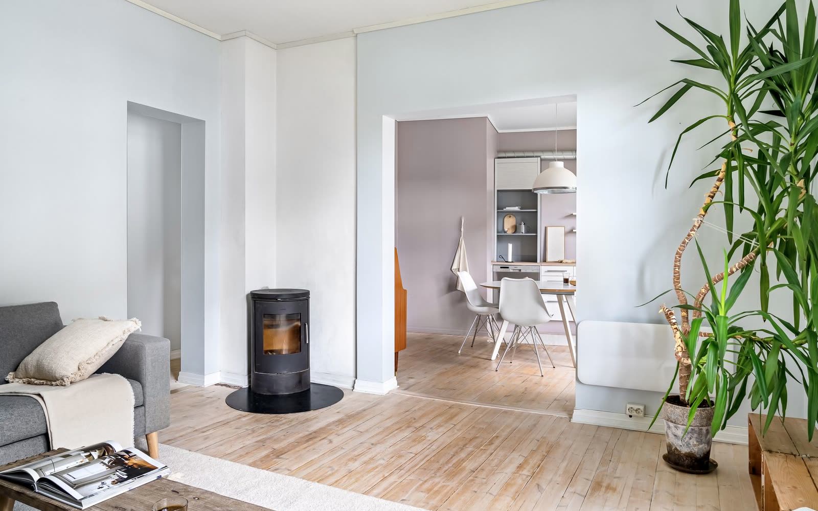 Vardagsrum med kamin, öppning mot kök och plankgolv