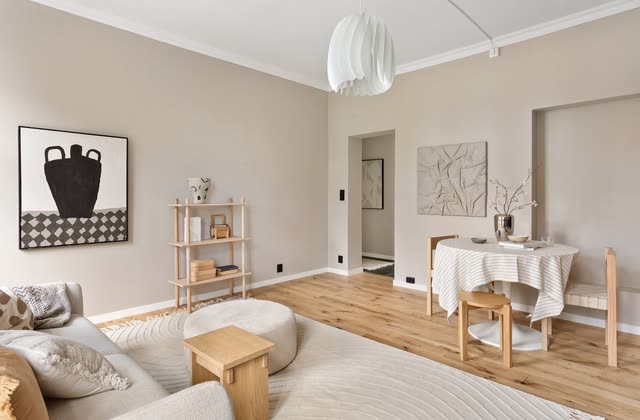 Beige sekelskiftesrum med soffa, matbord och stuckatur
