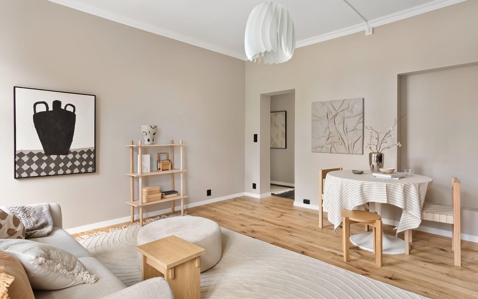 Beige sekelskiftesrum med soffa, matbord och stuckatur