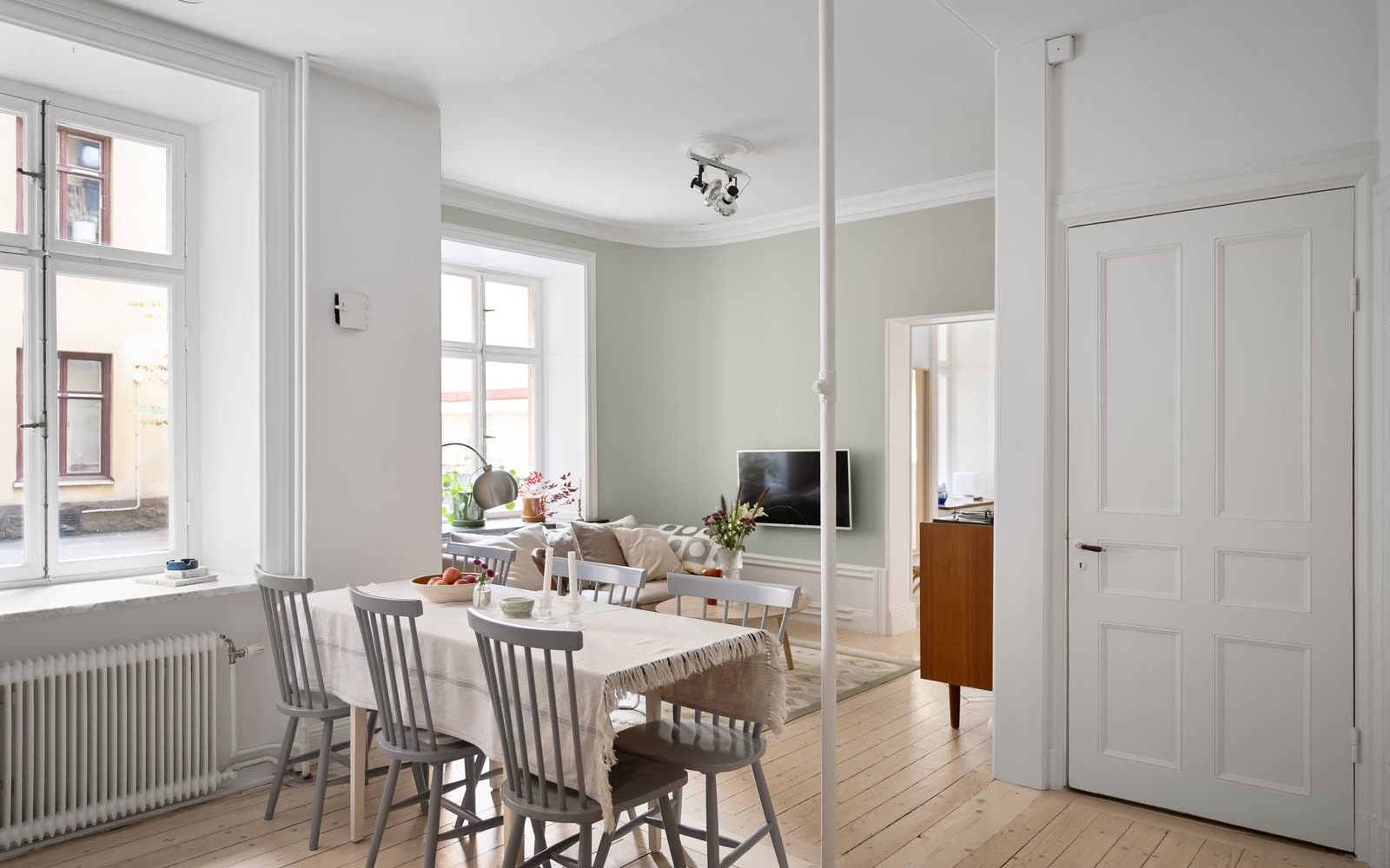 Öppen planlösning med matbord, pinnstolar och vardagsrum bortom