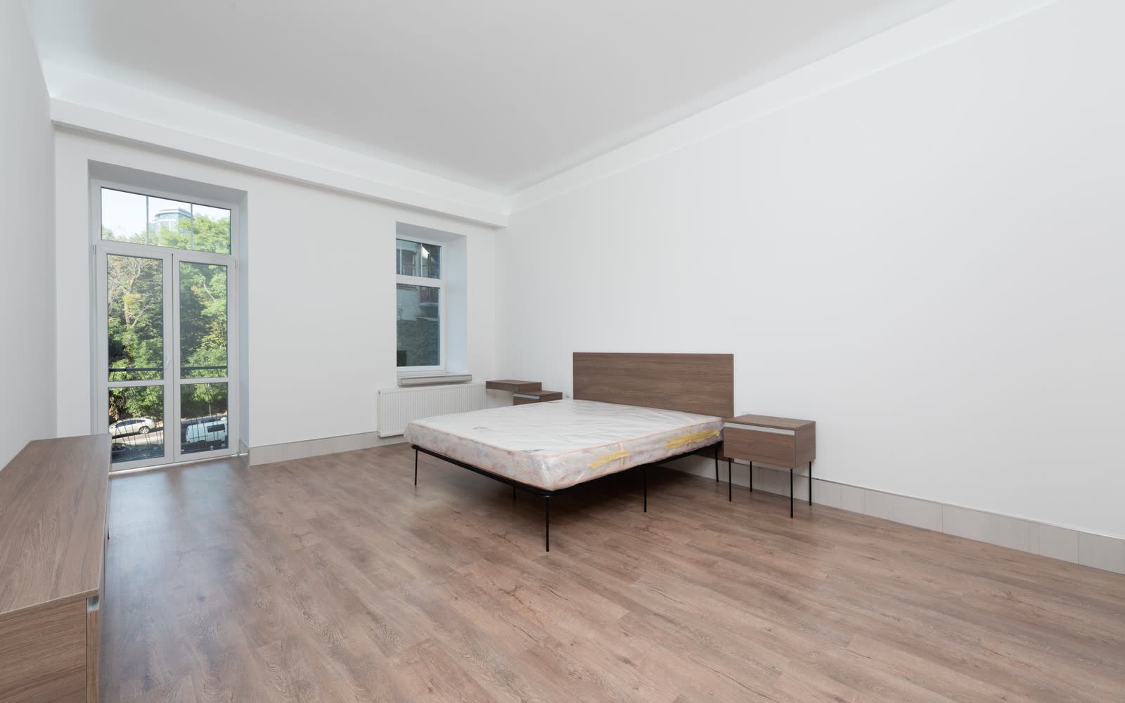 Tomt renoverat sovrum med balkongdörr, radiator och ekgolv