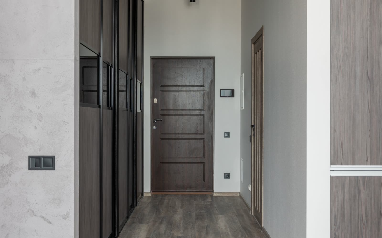 Hall med garderobsvägg och mörk ytterdörr