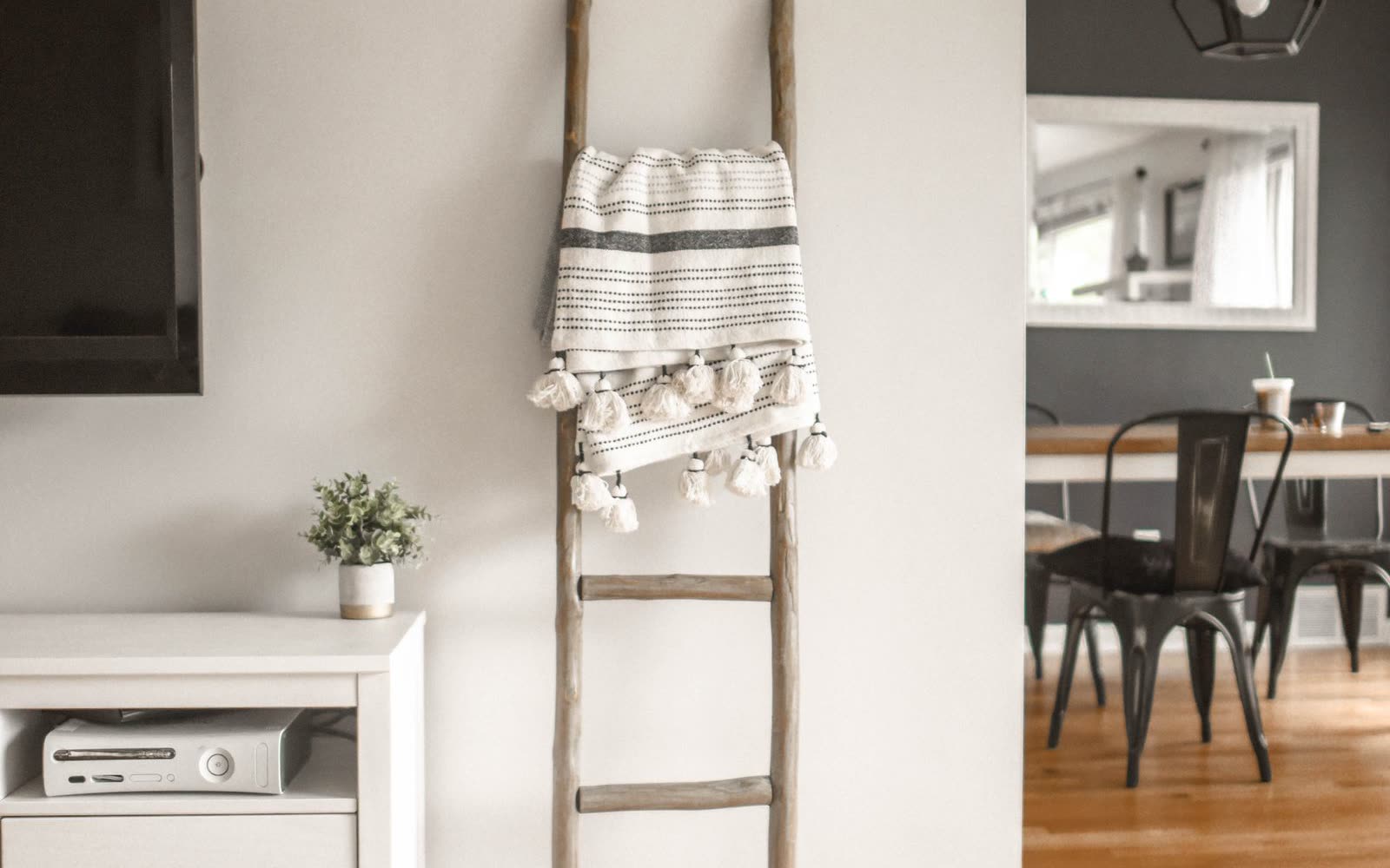 Ljust vardagsrum med tv, dekorstege och matplats i bakgrunden