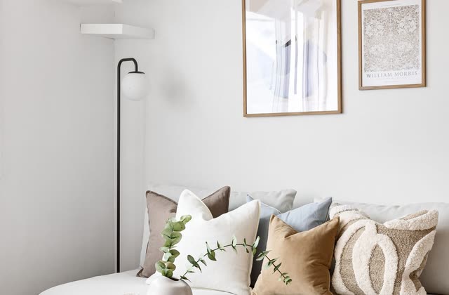 Soffhörna med vit soffa, tavlor och runt soffbord