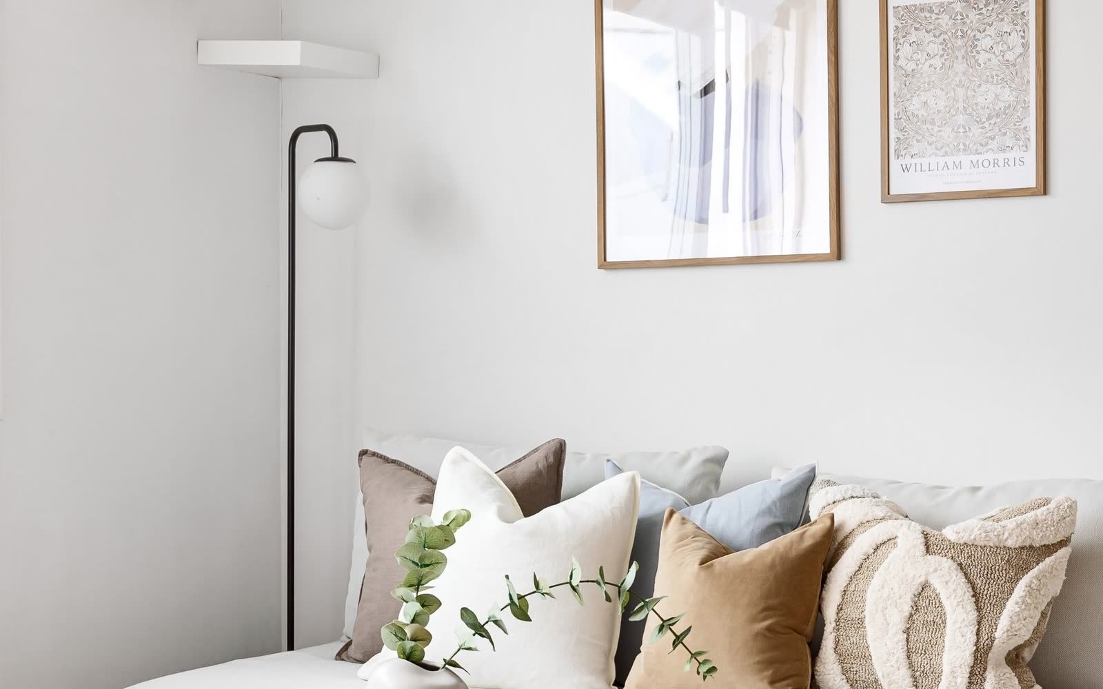 Soffhörna med vit soffa, tavlor och runt soffbord